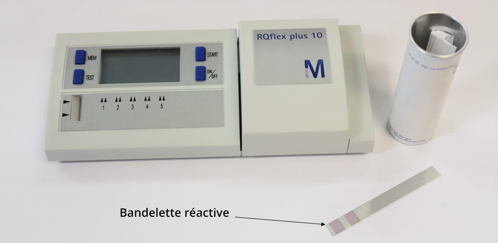 Photo d'un réflectomètre, avec à sa droite une boite contenant des bandlettes réactives