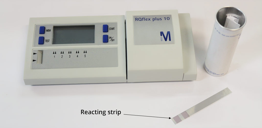 Photo of a reflectometer, with on its right a box containing reactive strips